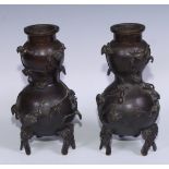 A pair of Chinese brown patinated bronze double gourd vases, cast and applied with trailing vine and