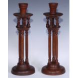 A pair of Arts and Crafts period oak candlesticks, each flared sconce upon a circular plateau
