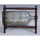 Folk Art - a 19th century model ship in a bottle, mahogany stand, 30cm wide