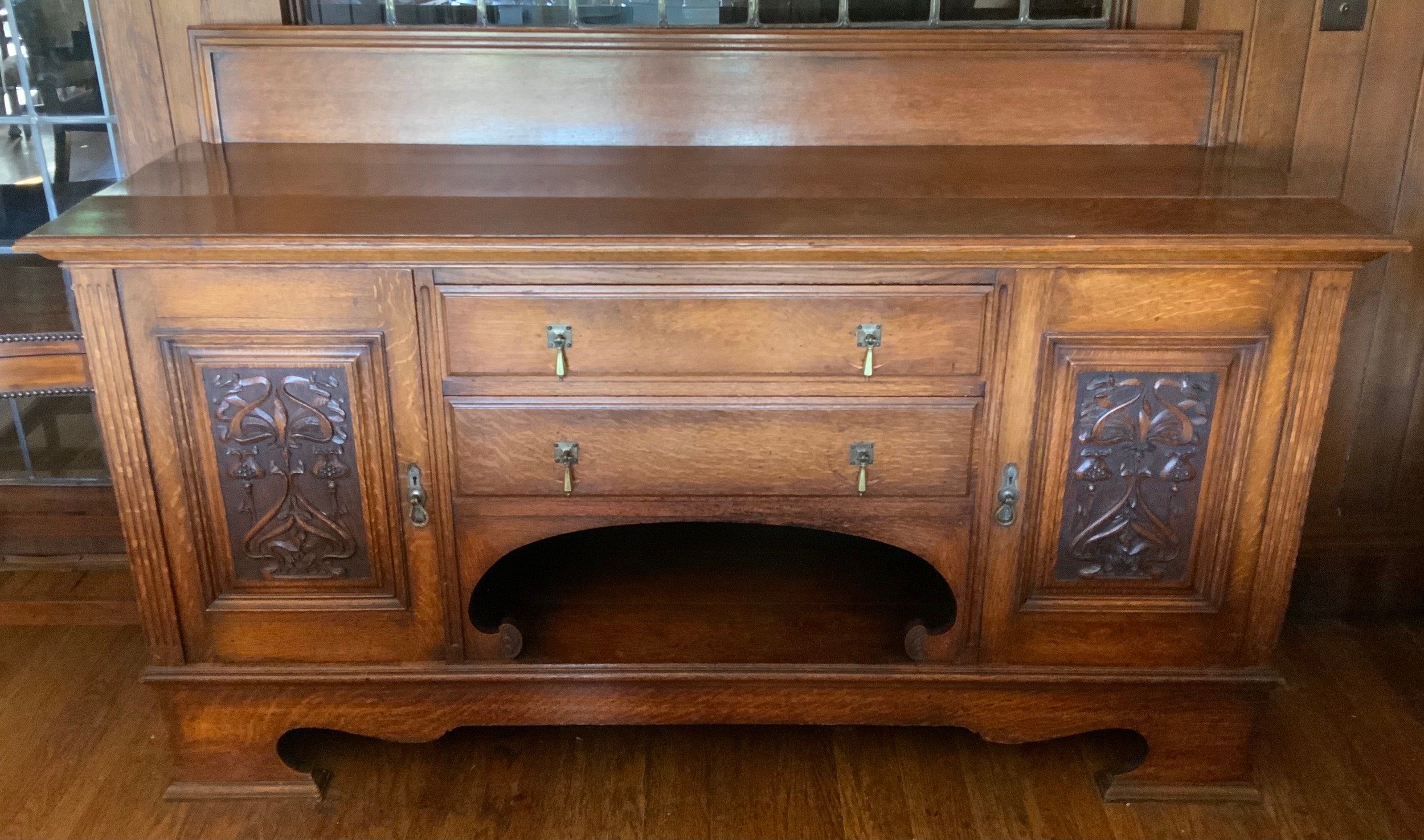 An Edwardian oak sideboard, fitted with two drawers, and two panelled doors, carved with scrolls,