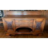 An Edwardian oak sideboard, fitted with two drawers, and two panelled doors, carved with scrolls,