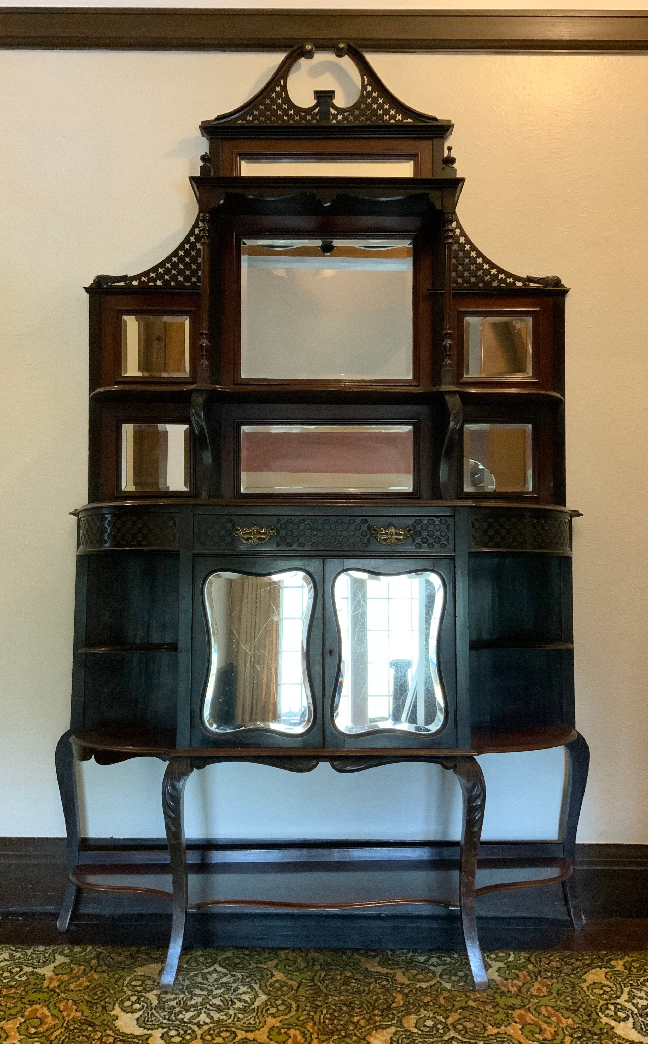 A Victorian ebonised chiffoniere, with blind fret swan neck pediment above two shelves and seven