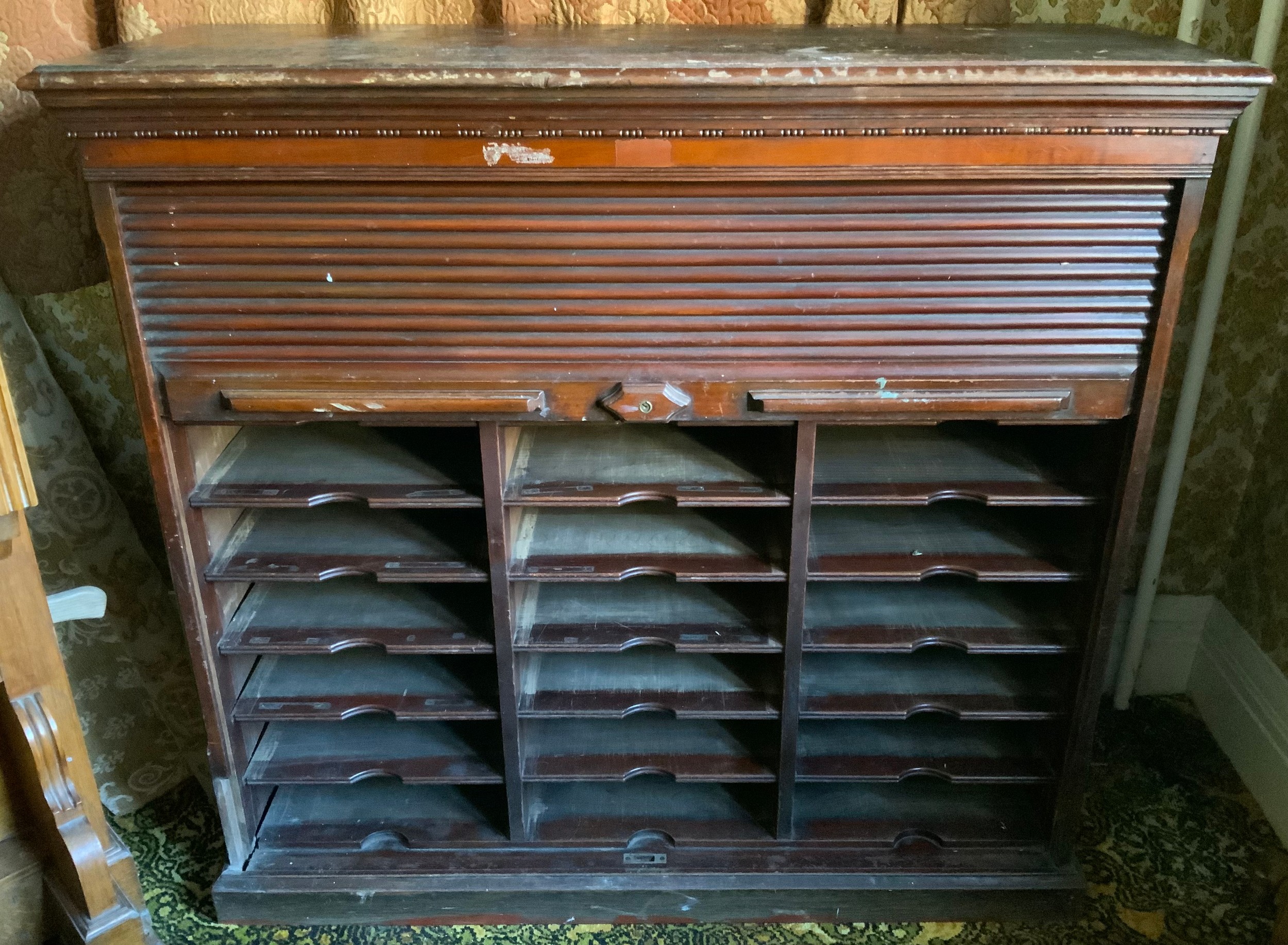 A late 19th century mahogany tambour front cabinet, egg-and-dart frieze, the interior with three