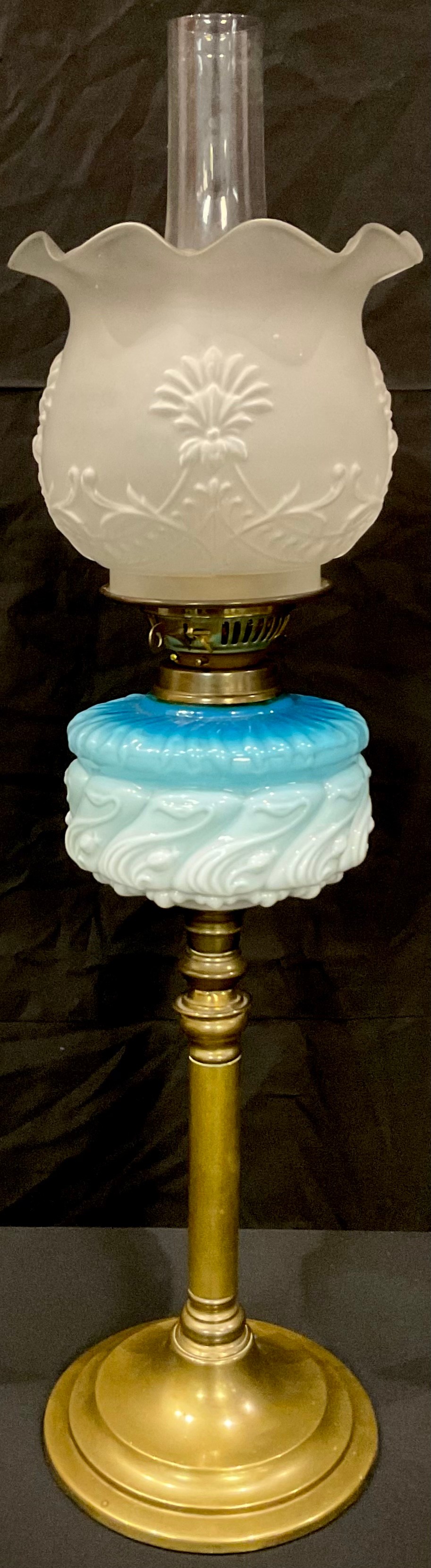 An Art Nouveau oil lamp, frosted glass shade, moulded blue and milk glass font, brass column on
