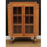 An Art Deco limed oak display cabinet, shallow half gallery above a pair of glazed doors enclosing