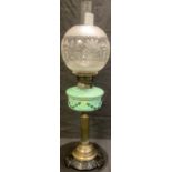 A 19th century oil lamp, spherical frosted glass shade, painted green glass font supported by a