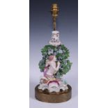 A 19th century figural lamp, moulded with a Cupid before bocage, shell and scroll base, 42cm overall