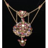 A Baroque style pendant, set with semi precious stones and pearls on a scrolling openwork enamel