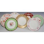 A Royal Crown Derby shaped circular plate, the field with three roses, within a shaped reserve, ruby