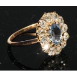 An early 20th century diamond and blue topaz cluster, the central oval stone within 12 diamonds,