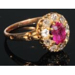 A diamond and ruby cluster ring, the central oval facet cut ruby set within within nine brilliant