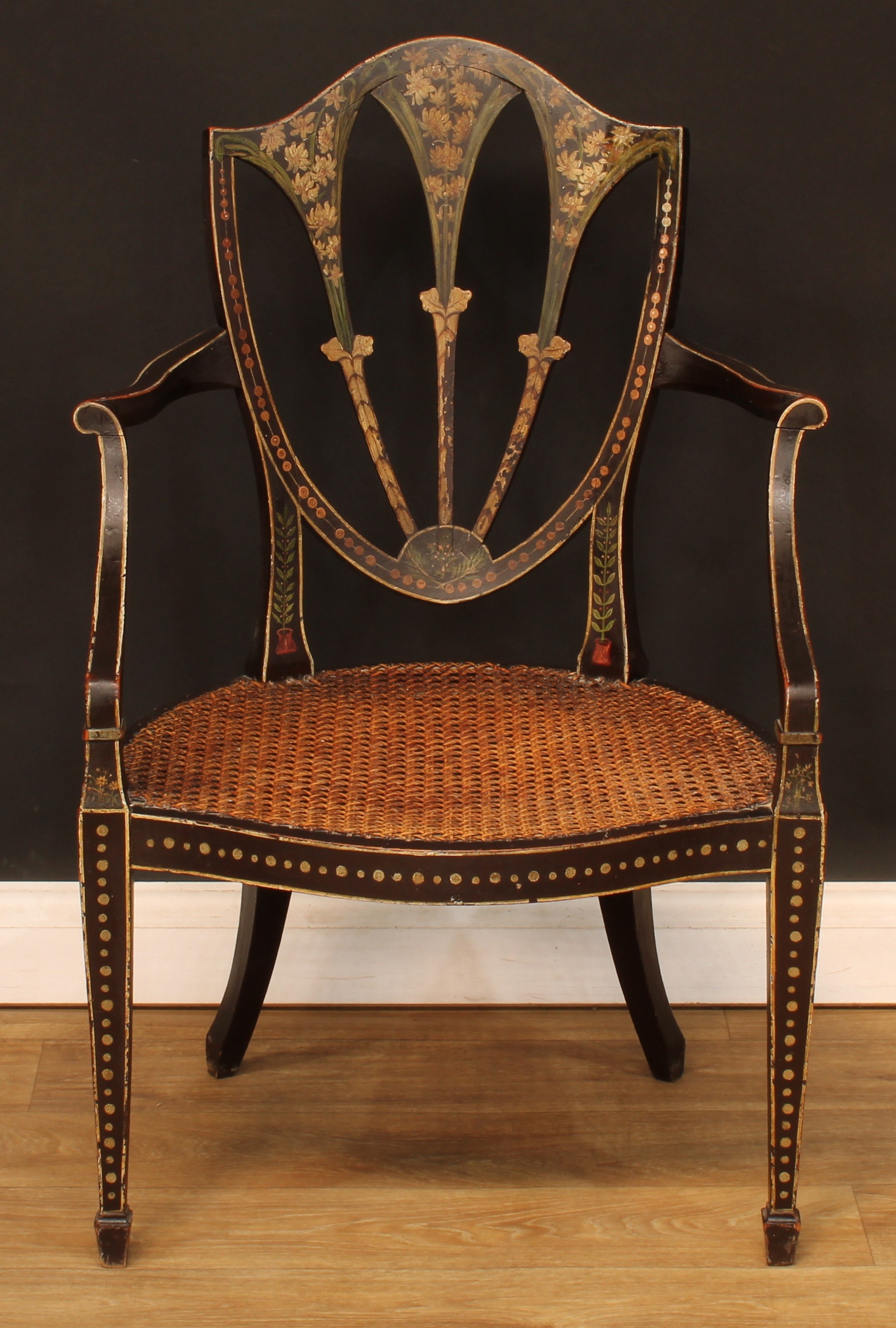 A Hepplewhite Revival painted and ebonised open armchair, cane seat, tapered square forelegs,