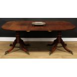 A George III mahogany twin-pillar dining table, rounded rectangular top with one additional leaf,