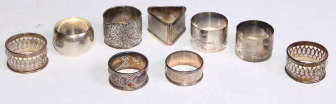 A George V silver triangular napkin ring, engine turned, Birmingham 1920; eight other silver