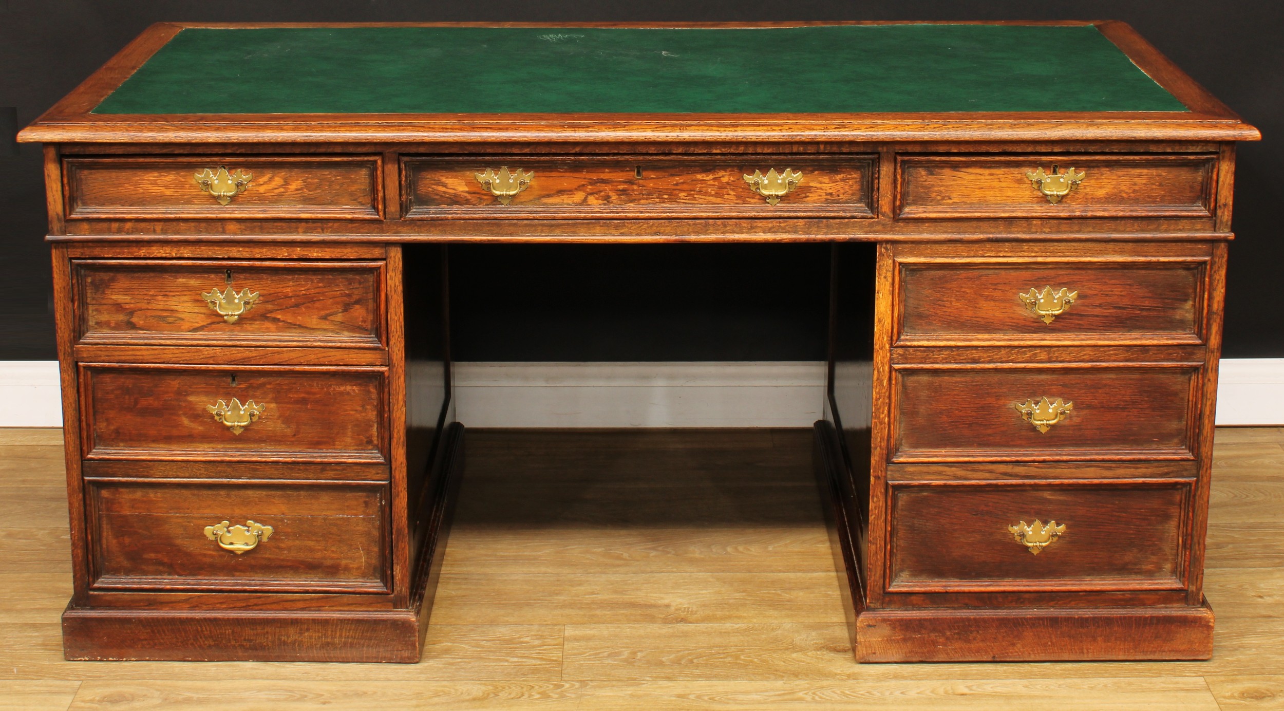 An oak twin pedestal desk, rectangular top with inset writing surface above three frieze drawers,