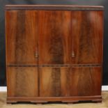 An early 20th century mahogany wardrobe, blind fretwork cornice above three doors, fitted with linen