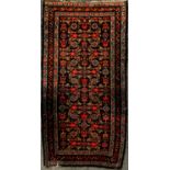 A Persian woollen rug, the central field with geometrical floral roundels, banded borders, 111cm