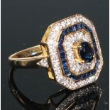 An Art Deco style canted rectangular sapphire and diamond cluster ring, the central raised oval