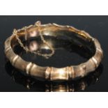 A 9ct gold hinged bangle hollow cast with 'linked bones', 7.25cm in diameter, 12.1g