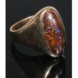 A black opal and 9ct gold ring, the large elongated oval cabochon stone set within within a plain