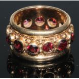 A 14ct gold eternity ring, set with a band of colette set facet cut garnets, within ripe twist and