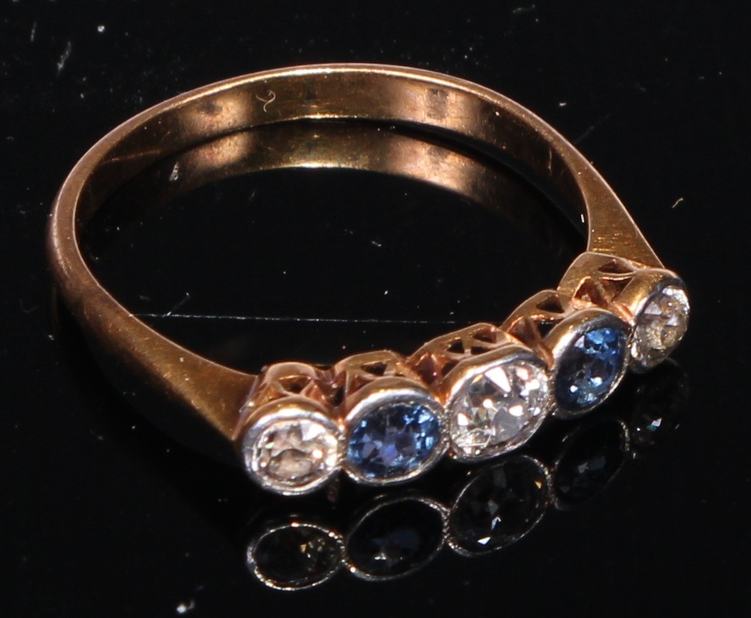 A five stone diamond and sapphire ring, the three diamonds divided by two sapphires, gold coloured