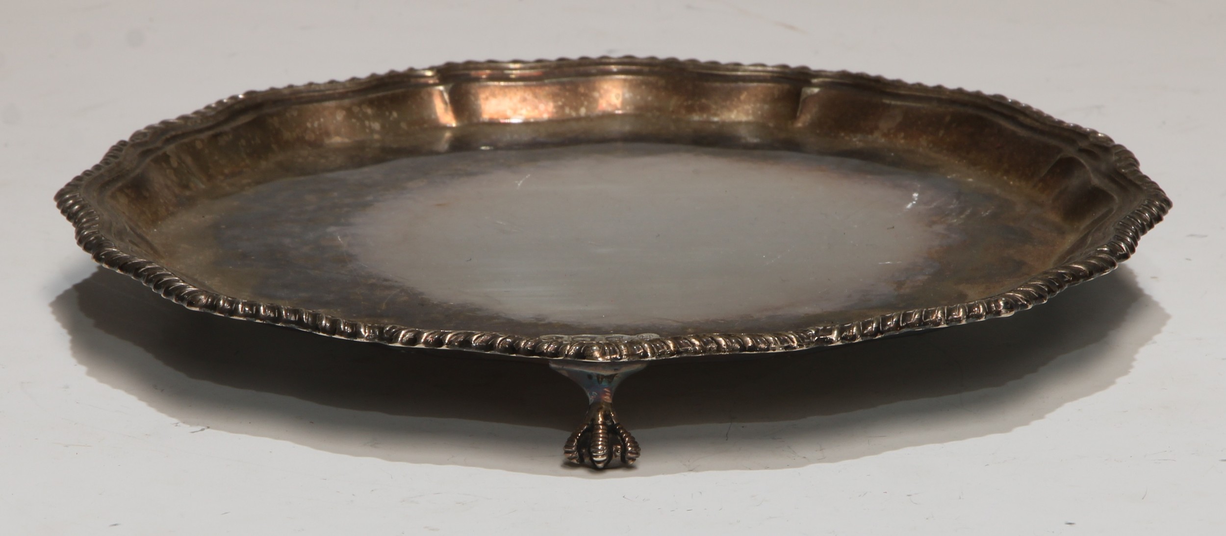 A George III style silver shaped circular waiter, plain field, ball and claw feet, 20.5cm diam,