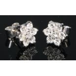 A pair of seven stone diamond flowerhead cluster stud earrings, set in white metal