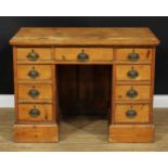 A George III pine kneehole desk, oversailing top above an arrangement of drawers, oval brass