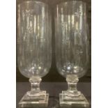 A pair of glass storm lanterns, each decorated with eight-pointed stars, stepped square bases,