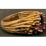 A 9ct gold modernist ring, set with a single oval cut amethyst, surrounded by fronds of gold, size