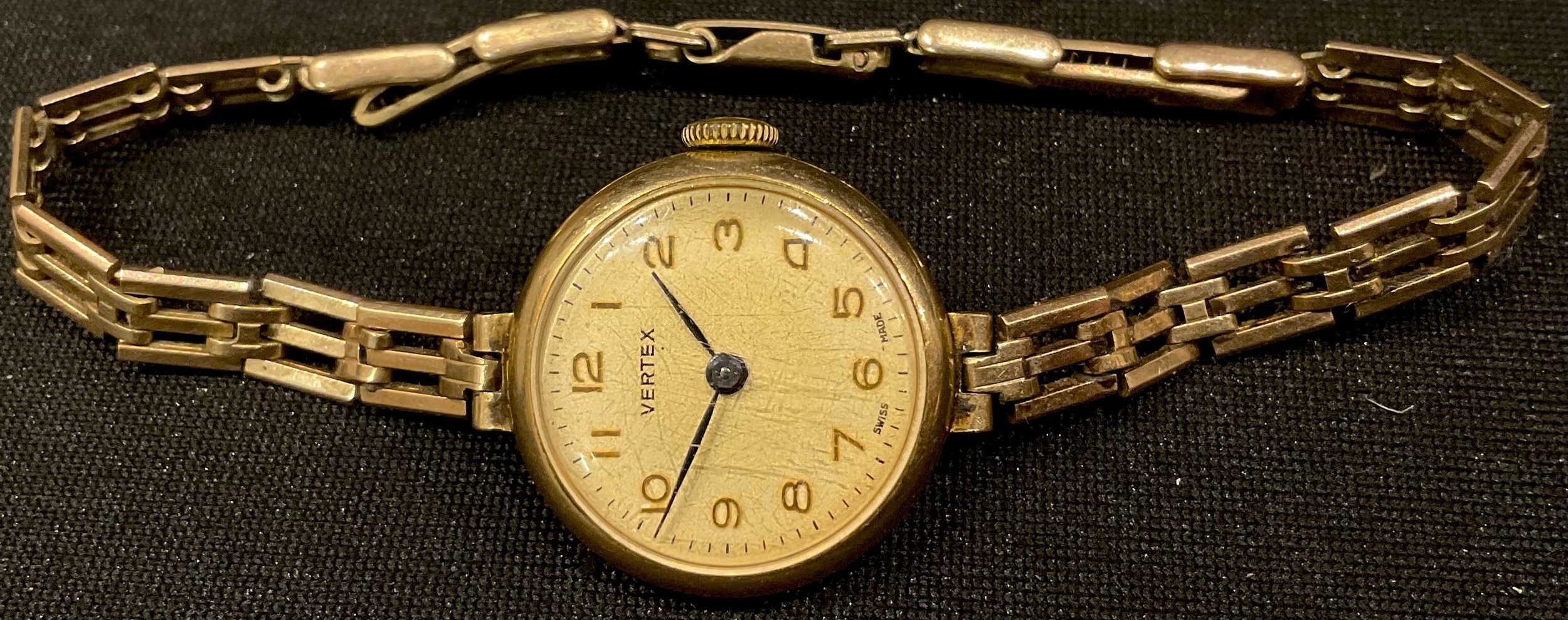 A 9ct gold ladies Vertex wrist watch, champagne dial, Arabic numerals, side wind, articulated strap,