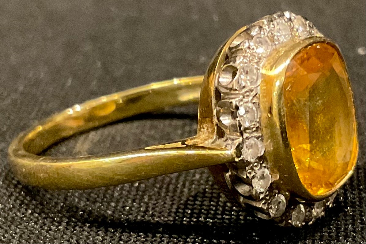 An 18ct gold yellow sapphire and diamond ring, the central cusion cut stone surrounded by sixteen