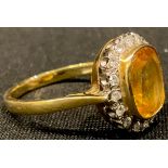 An 18ct gold yellow sapphire and diamond ring, the central cusion cut stone surrounded by sixteen