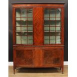 An Edwardian mahogany display cabinet, outswept cornice above a pair of doors enclosing two shelves,