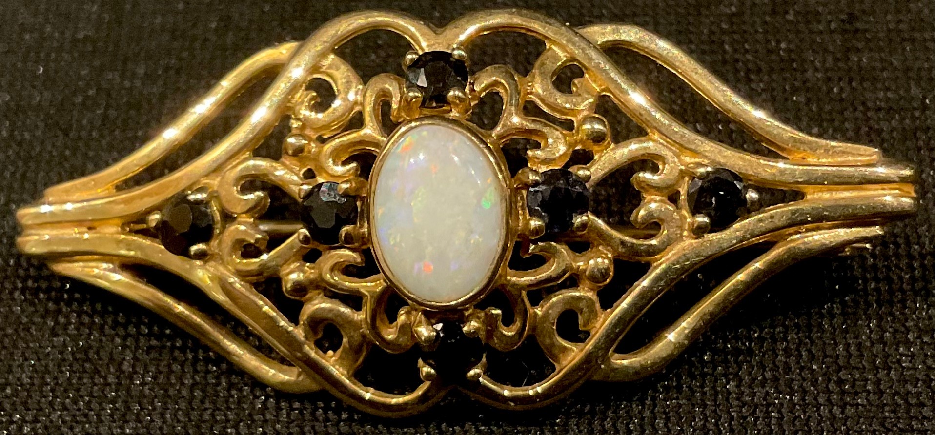 A 9ct gold brooch, set with a central polished opal, surrounded by six smaller sapphires, 4cm, 3.6g