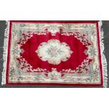 A Chinese Kayam woollen rug, the field with stylised flower within an oval cartouche on a red