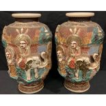 A pair of Japanese export ware Satsuma type vases, moulded in relief with a procession of deities