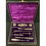 An early 20th century nine piece manicure set, comprising scissors, silver hafted tools, silver