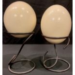 A pair of ostrich eggs on metal wire stands, 28cm