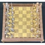 A chess set, with silver plated and gilt pieces, in oriental manner, 38cm wide
