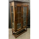 A Priory style small oak side cabinet, glazed doors and sides enclosing three tiers of shelving,