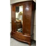 An early 20th century mahogany bow-front wardrobe, moulded cornice, single central mirrored door