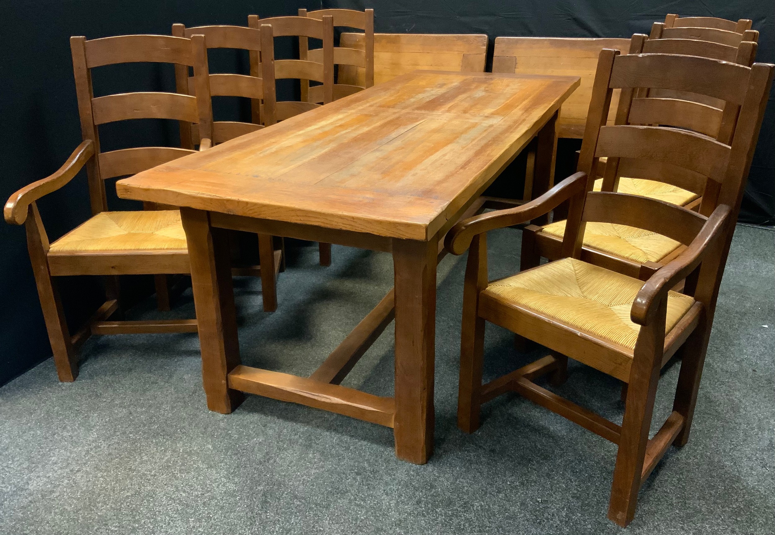 A large oak trestle dining table with eight rush-seated dining chairs (six chairs and two