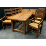 A large oak trestle dining table with eight rush-seated dining chairs (six chairs and two