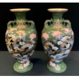 A pair of Chinese twin handled vases, decorated with dragons flying amongst clouds, 41cm high (2)