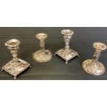 A pair of silver boudoir candlesticks, embossed overall with scrolling foliage, 10cm high,