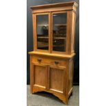 An early 20th century, Arts and Crafts style, oak bookcase cabinet, moulded cornice, pair of