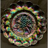 A purple Carnival glass shaped circular dish, moulded with a bunch of grapes and vine leaves, 27.5cm