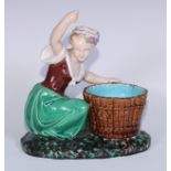 A Minton majolica figure, of a lady kneeling by a basket, her arm raised, in colours, 22cm high,